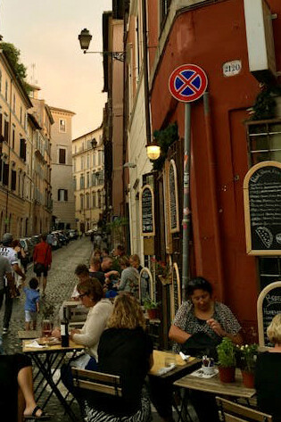 People dining at a cozy street restaurant in Rome, Italy, enjoying a warm Roman evening outdoors