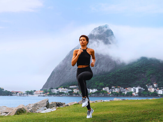 A woman jogging along a scenic waterfront, representing the uplifting impact of regular movement on mental well-being