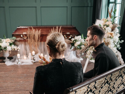 Overcome with grief, a woman pays her final respects beside a coffin covered with floral tribute