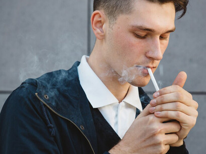 A young man smoking outdoors
