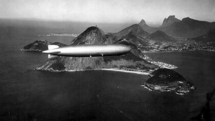 Dirigível LZ 127 "Graf Zeppelin" sobre o Rio de Janeiro. Estávamos todos juntos, minha mãe, meu pai, meus irmãos. Meus pais tinham me dado a permissão rara de andar um pouco mais longe, mas eu sabia que não podia ir muito além da barraca da pipoca. Ainda assim, minha curiosidade me empurrava, como sempre fazia