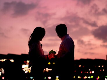 A couple cradling a glowing lantern beneath the evening sky, representing hope carried through years of waiting and sacrifice