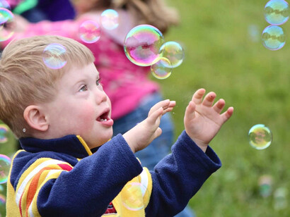 Un niño con síndrome de Down juega con pompas de jabón