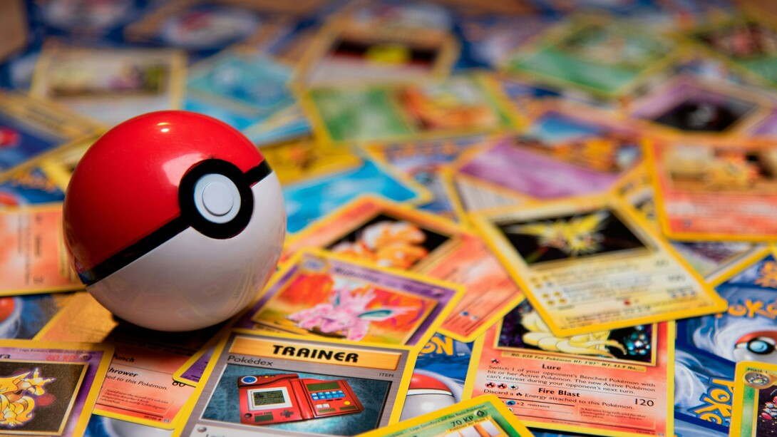 A Poké Ball resting among scattered vintage trading cards, representing the transformation of childhood hobbies into valuable collectibles