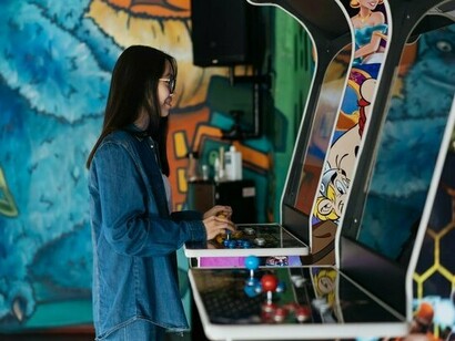 A girl interacting with a retro arcade game, symbolising the emotional power of gaming nostalgia