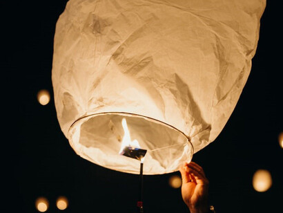 A person releasing a sky lantern into the night sky