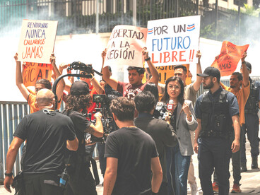 Protesters stand in a smoke-filled street holding signs, San José, Costa Rica
