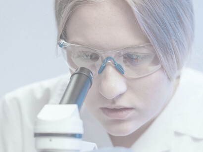 Eine Wissenschaftlerin führt akribische Forschungen durch und nutzt dabei ein Mikroskop in der kontrollierten Umgebung eines Labors