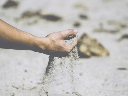 Un hombre coge un puñado de arena en una playa solitaria