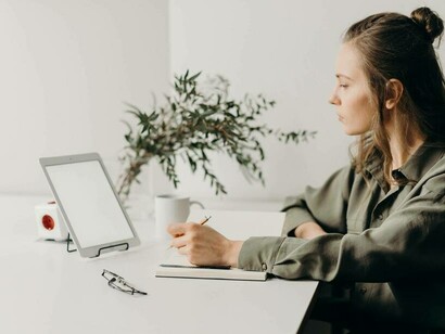 A woman taking down notes from her tablet in her startup role