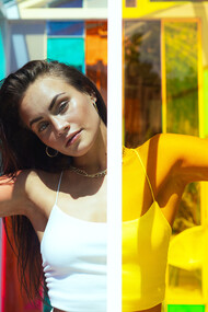 Modelo detrás de una vitrinas de distintos colores. Un color bien elegido puede enfatizar tu mirada, iluminar tu cara o potenciar el brillo de tu cabello