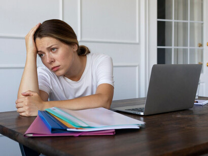 A woman sitting on a chair, overwhelmed and upset by financial difficulties