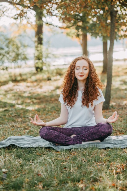 A young woman doing a meditation on the grass, self-care and self-love, and doing healthy things for your well-being is extremely important and necessary