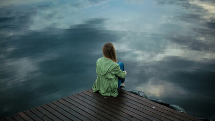 A woman sitting on wooden planks, deep in thought or reflection