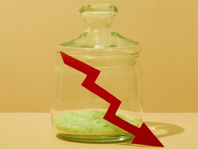 The downward-pointing arrow and minimal rice in the jar symbolize the failing economy and potential bankruptcy discussed in the article