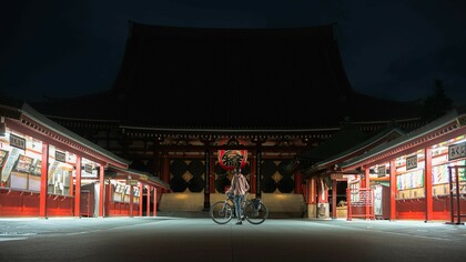 A man riding a bike in front of Sensoji Temple, Asakusa, alone under the moonlight at midnight, with the temple's iconic architecture bathed in soft, serene light, Japan