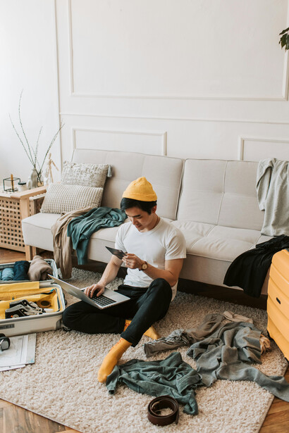 Man listening to music on his headphones while packing his clothes, a travel blogger preparing for a trip