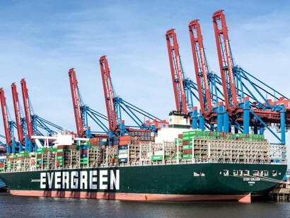 At the Port of Hamburg, industrial cranes lift containers onto a cargo ship for international transport