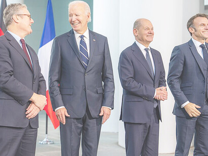Former President Joe Biden chats with U.K. Prime Minister Keir Starmer while posing for a family photo alongside Starmer, German Chancellor Olaf Scholz, and French President Emmanuel Macron during a "European Quad" leaders meeting on Friday, October 18, 2024, at the Chancellery in Berlin, Germany