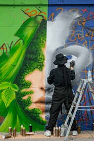 An artist creating graffiti on a wall