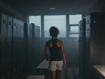 A female athlete in a professional locker room, surrounded by empty benches under dramatic, low lighting