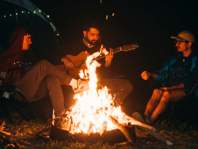 Friends enjoying live music in the warmth of a campfire, reflecting the beauty of experiences that leave memories instead of digital footprints