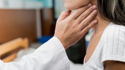 A hand touching the throat of a patient, symbolizing chronic illness, fatigue, exhaustion, and thyroid dysfunction
