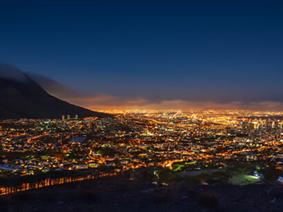 Stunning nighttime photography capturing the illuminated skyline of Cape Town, including landmarks like Robben Island and Lion's Head, showcasing urbanization in South Africa