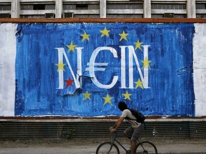 Un ciclista pasa frente a un mural en contra de la Unión Europea en Atenas