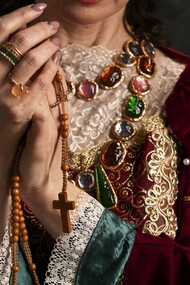 In a crimson velvet gown adorned with pearls and jewels, this figure illustrates how queens used opulent attire and accessories to shape enduring fashion trends