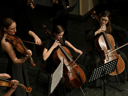 Donne in abiti neri intente a suonare violini e violoncello