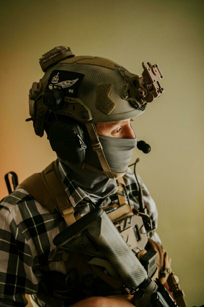 A soldier in tactical gear and military helmet, aiming in camouflage armor