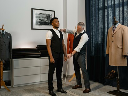 A tailor checking a garment’s fit and proportions on a model, reflecting the hands-on expertise that remains essential despite advances in AI