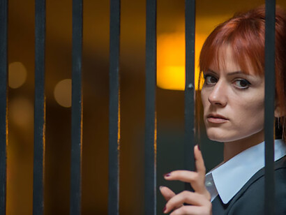 A female journalist stands behind prison bars, symbolizing the imprisonment of the press