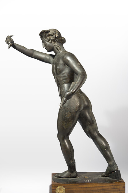Hypnos (Somnus), che versa il sonno sull’umanità
Firenze, Museo Archeologico Nazionale, inv. 1718 (già Galleria degli Uffizi, dal 1769). Alt. cm 44,5
Bronzo; fusione cava, con ritocchi a cesello.
Copia romana, degli anni tra il 50 e il 150 d.C., di un originale greco del IV o III sec. a.C. che raffigurava il dio del Sonno (figlio della Notte e fratello gemello di Thanatos, la morte), con le ali alle tempie e coronato di fiori di papavero, che vola sul mondo versando dal suo corno il magico “succo” affidatogli dal Giove per dispensare il sonno al genere umano.
Ph. Fernando Guerrini (Archivio Fotografico della Soprintendenza Archeologia della Toscana)