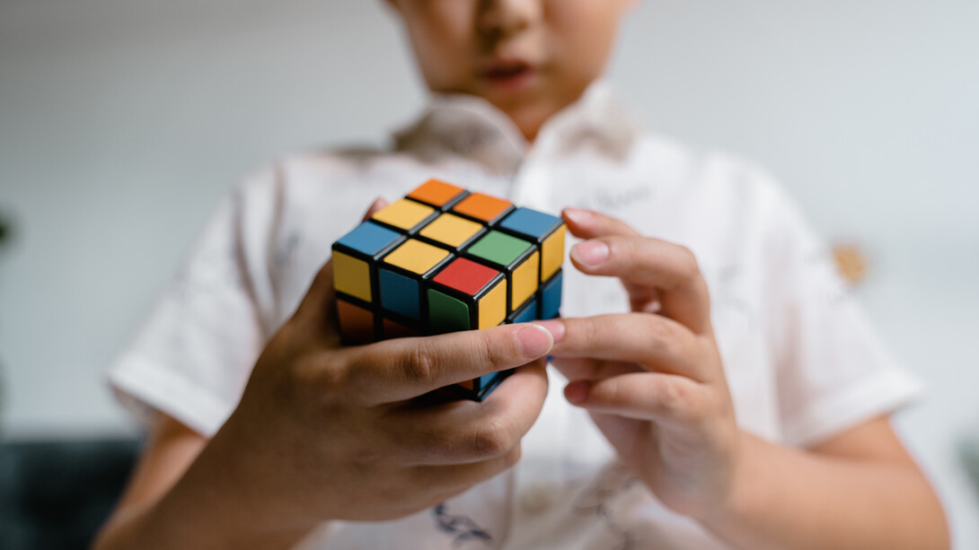 Criança participa de desafio com cubo mágico em uma gincana da escola