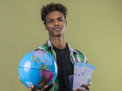 Confident young African American man traveling with luggage while carrying passport and visa papers
