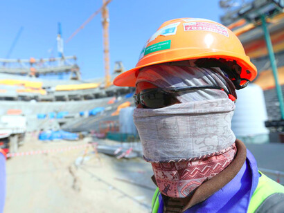 Un trabajador cubre su cara para protegerse del sol en la construcción de uno de los estadios de Qatar 2022