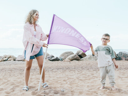 A son and his mother with a kindness flag together on the sand