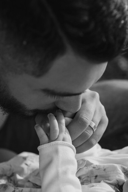 Un padre besando tiernamente las manitos de su hijo
