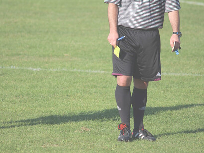 Arbitro in campo con cartellino giallo in mano