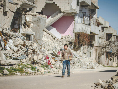 Amid the aftermath of a bombing, a young Syrian boy walks past demolished buildings, a silent witness to the toll of war