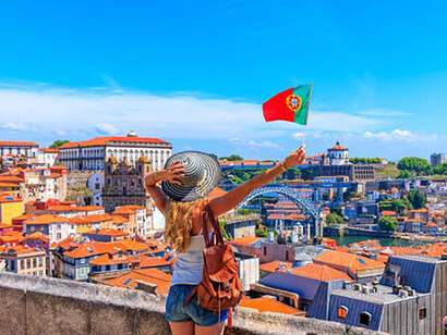 A female tourist proudly waves the Portuguese flag against the backdrop of a panoramic cityscape viewpoint in Porto, Portugal