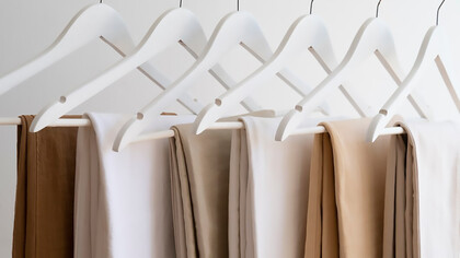 Light brown beige pants hanging on minimalist hangers, showcasing a sleek and simple style