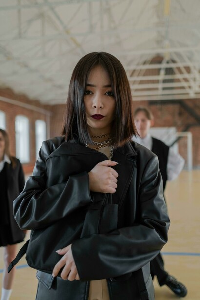Young girl in a black leather blazer holding her backpack, facing bullying at school