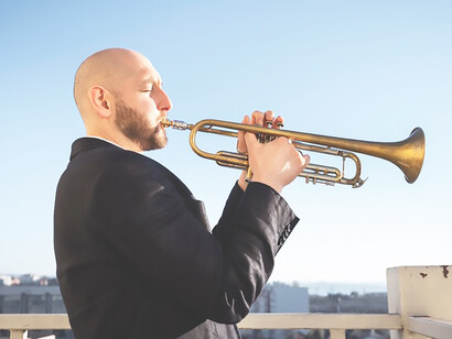 Indulge in a jazz-infused day by the seaside, featuring adult skillfully playing the trumpet amidst the soothing ambiance of the ocean, creating a perfect musical escape