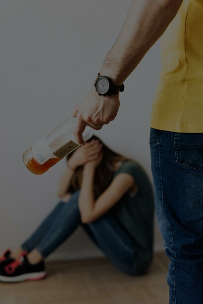 Homem segurando uma garrafa perto de uma mulher sentada cobrindo o rosto
