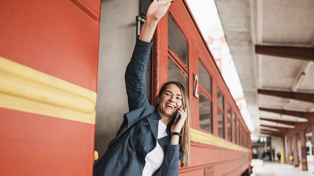 Empowered woman standing at train entrance, waving, symbolizing commitment to progress and positive change
