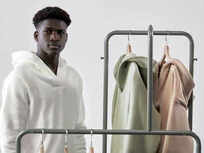 A man thoughtfully selecting minimalist menswear from a clothing rack