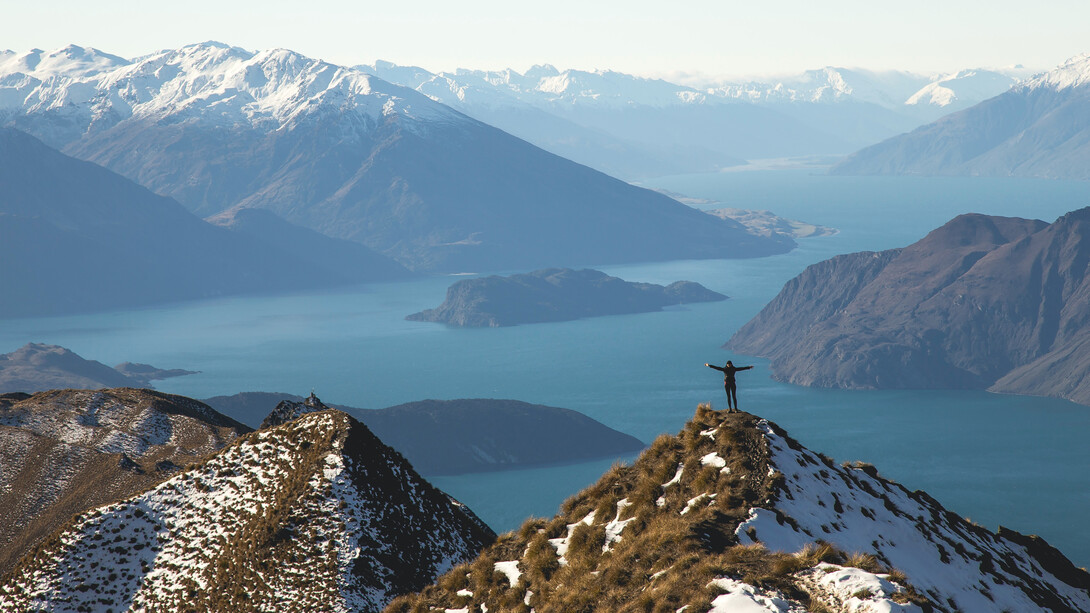 Persona en la cima de una montaña: creer en ti te aportará fuerzas para levantarte cada día sin perder la ilusión en tu proyecto